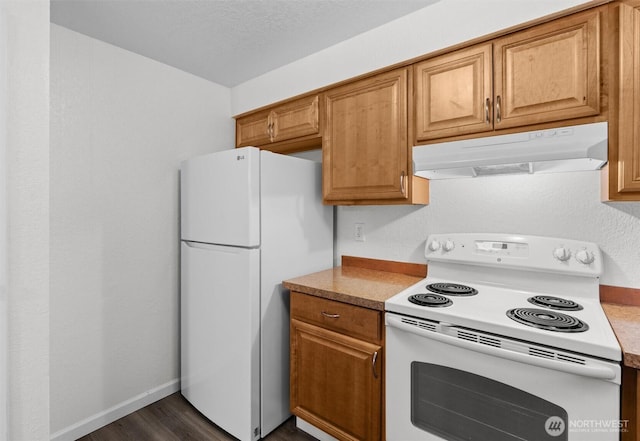 kitchen with baseboards, white appliances, brown cabinets, and under cabinet range hood