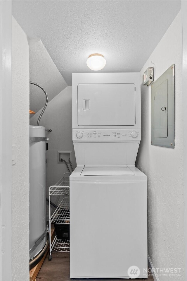 washroom with laundry area, stacked washer / dryer, wood finished floors, electric panel, and strapped water heater