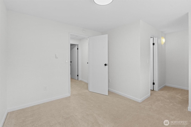 spare room with baseboards and light colored carpet