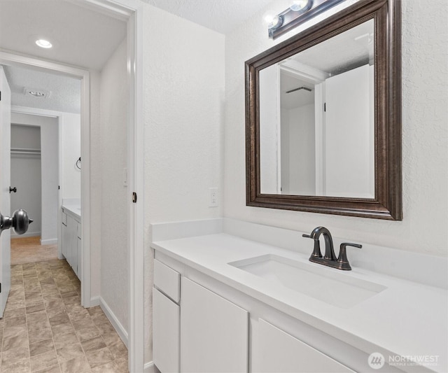 bathroom featuring a textured wall, vanity, and a textured ceiling