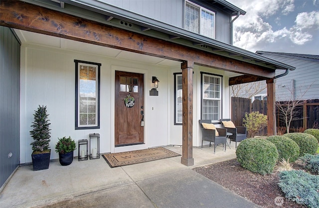 property entrance featuring covered porch and fence