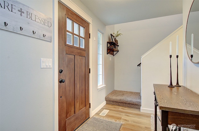 foyer entrance with stairs, light wood-style floors, visible vents, and baseboards