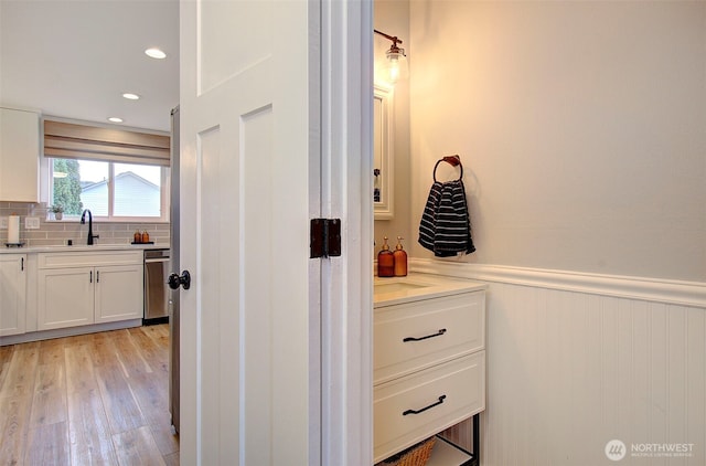 bathroom featuring vanity, decorative backsplash, wood finished floors, and wainscoting