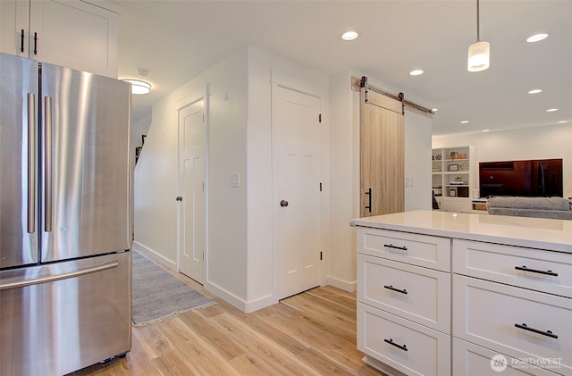 kitchen featuring a barn door, light wood-style flooring, white cabinets, and freestanding refrigerator