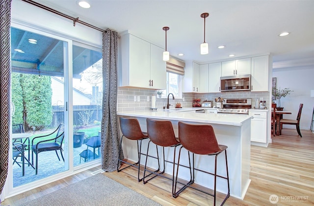 kitchen featuring a breakfast bar, light wood-style flooring, white cabinetry, and stainless steel appliances