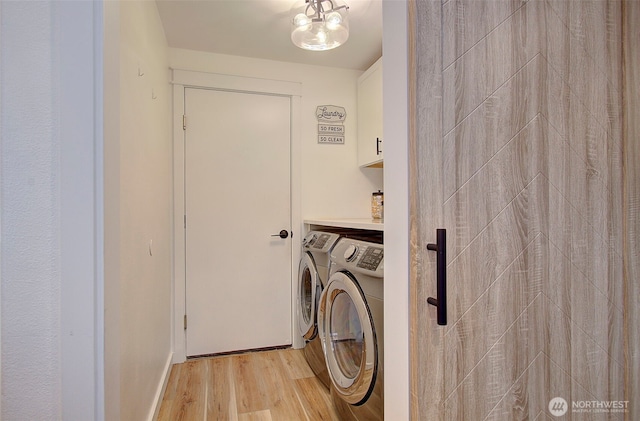 laundry area featuring cabinet space, light wood-style floors, and washer and clothes dryer