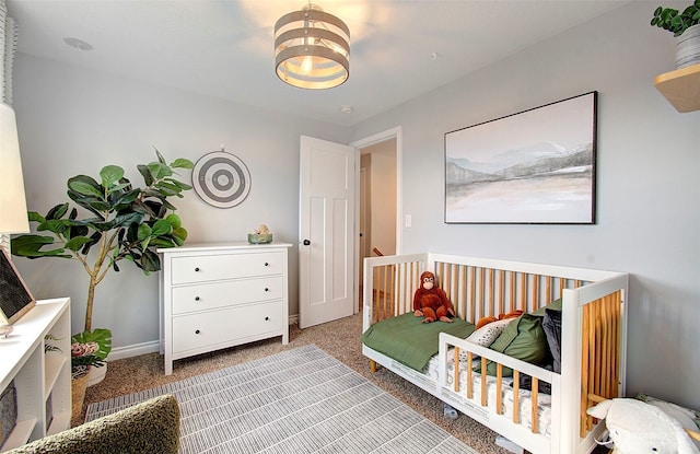 bedroom featuring light colored carpet and a nursery area