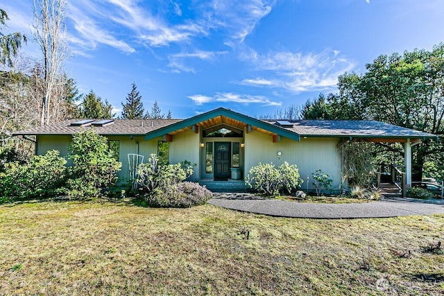 view of front of property featuring a front yard and solar panels