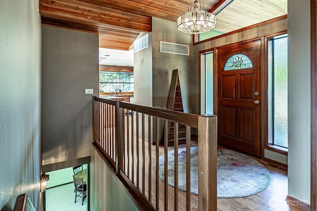 foyer entrance with a notable chandelier, wood ceiling, visible vents, and wood finished floors