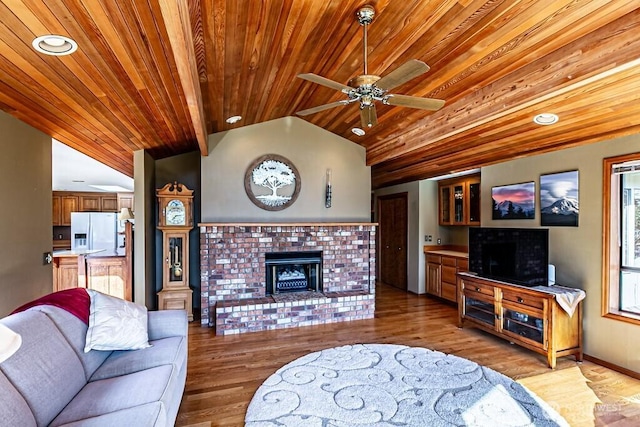 living room featuring lofted ceiling, ceiling fan, wood ceiling, light wood-type flooring, and a brick fireplace