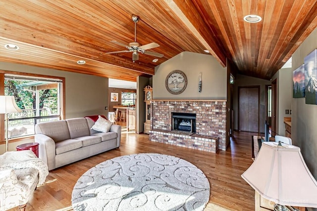 living room with lofted ceiling, wooden ceiling, a brick fireplace, and wood finished floors