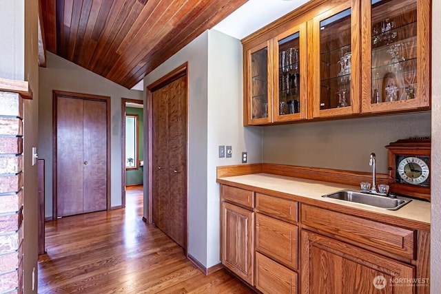 kitchen featuring lofted ceiling, light wood-style flooring, a sink, wood ceiling, and light countertops