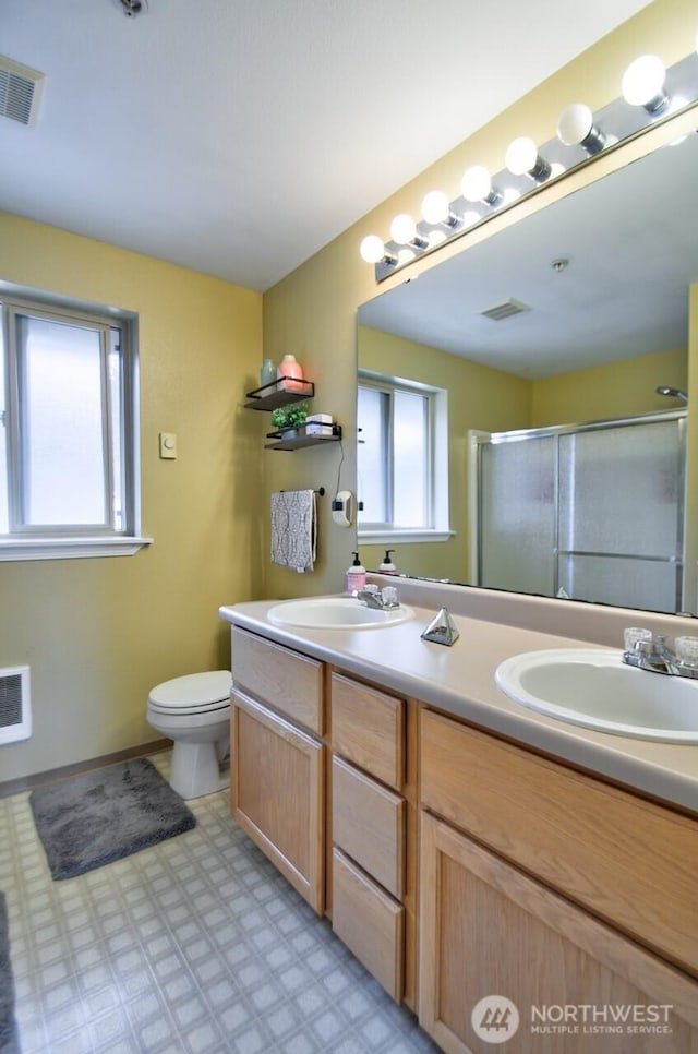 full bath with toilet, a stall shower, visible vents, and a sink