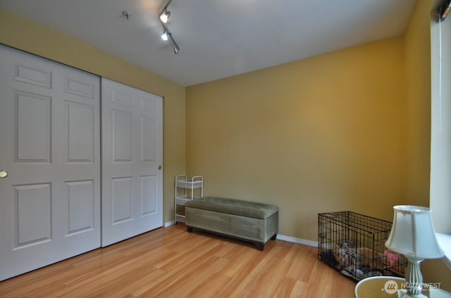 sitting room featuring rail lighting, baseboards, and wood finished floors