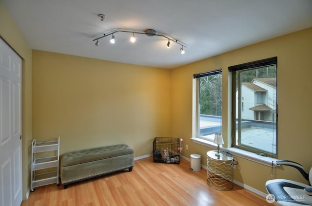 sitting room with track lighting, baseboards, and wood finished floors