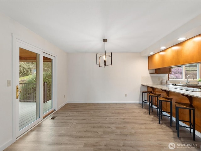 dining room with light wood-type flooring, visible vents, and baseboards