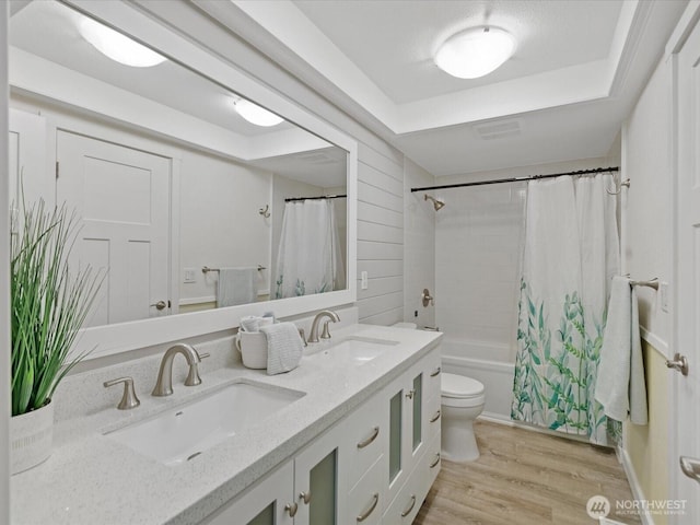 bathroom with toilet, double vanity, a sink, and wood finished floors