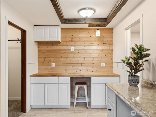 kitchen with wood walls, white cabinetry, and wooden counters