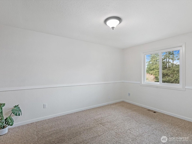 carpeted spare room featuring a textured ceiling, visible vents, and baseboards