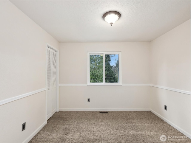 unfurnished room with carpet, visible vents, and baseboards