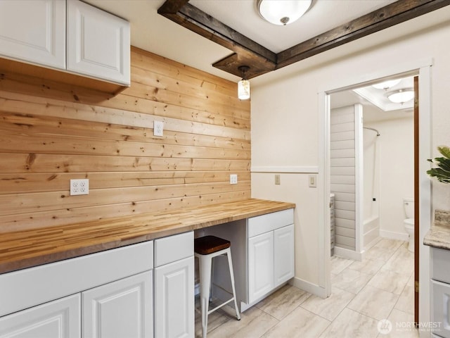 interior space with butcher block counters, white cabinetry, and wooden walls