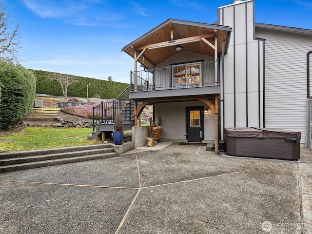 back of property featuring a patio, a hot tub, a balcony, and stairs