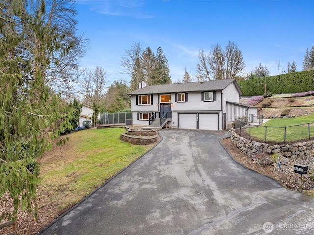 bi-level home featuring a chimney, fence, a garage, driveway, and a front lawn