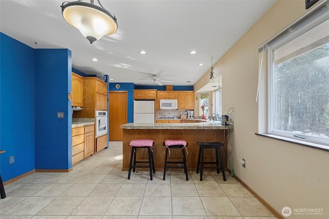 kitchen with a breakfast bar, tasteful backsplash, white appliances, a peninsula, and light tile patterned floors