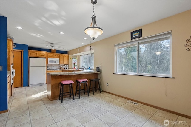 kitchen featuring white appliances, light tile patterned floors, visible vents, a peninsula, and decorative backsplash