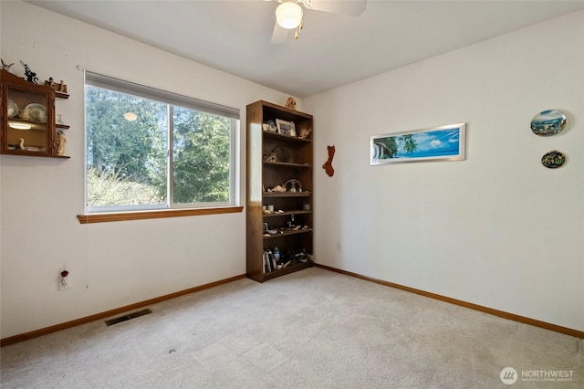 spare room with a ceiling fan, baseboards, visible vents, and carpet floors