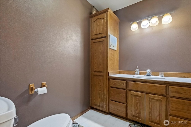 bathroom featuring baseboards, toilet, and vanity