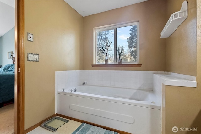 full bath featuring ensuite bath, a bath, and baseboards