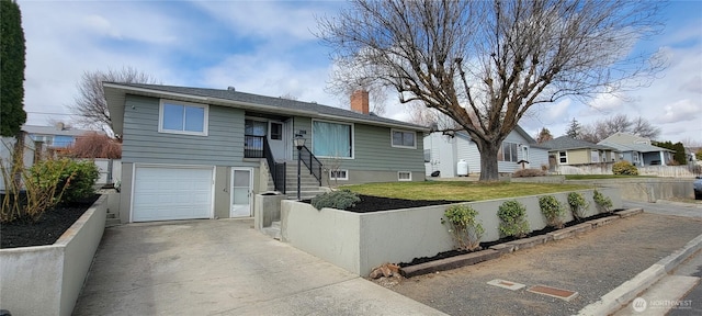 view of front facade with a fenced front yard, concrete driveway, a chimney, and an attached garage