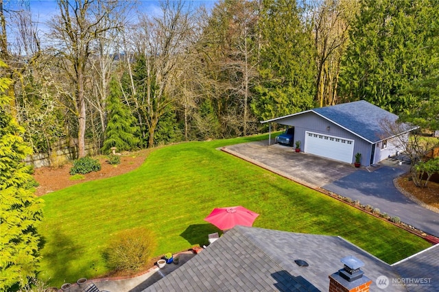 exterior space featuring aphalt driveway, an attached garage, and a forest view