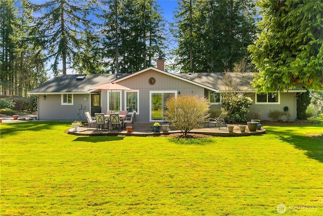 back of house featuring a patio, a lawn, and a chimney