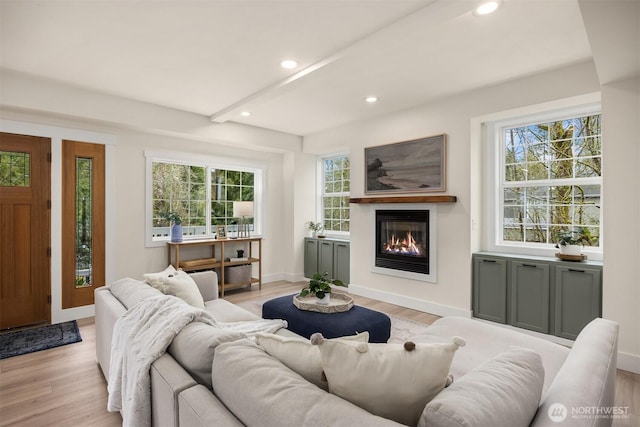 living room featuring recessed lighting, plenty of natural light, a glass covered fireplace, and light wood finished floors