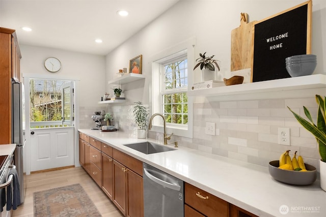 kitchen featuring a sink, brown cabinets, appliances with stainless steel finishes, light wood-style floors, and open shelves