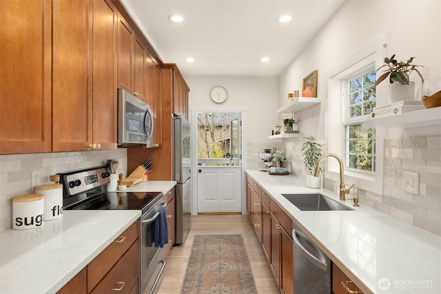 kitchen with open shelves, a sink, appliances with stainless steel finishes, brown cabinetry, and light countertops