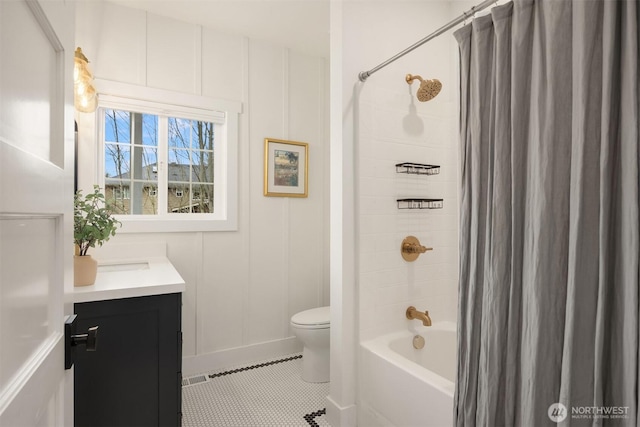 bathroom featuring vanity, shower / bath combo, tile patterned floors, a decorative wall, and toilet