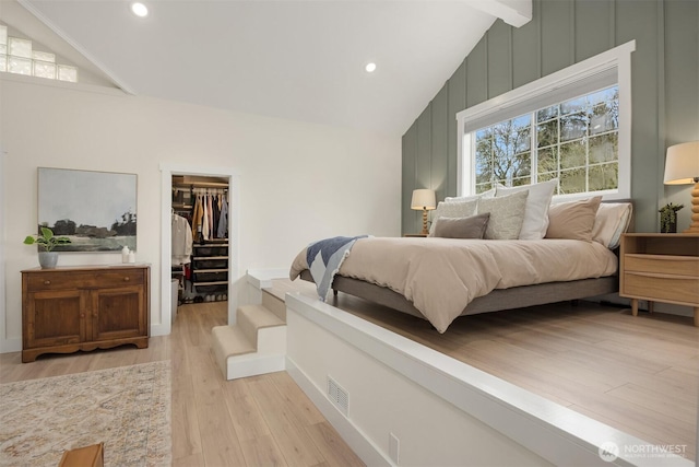 bedroom featuring visible vents, light wood-style flooring, vaulted ceiling with beams, a spacious closet, and a closet