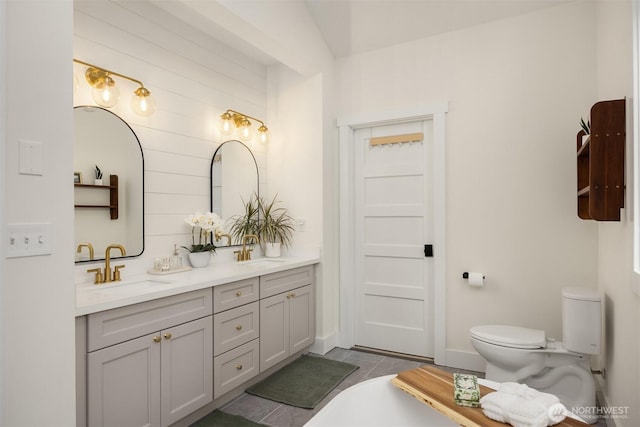 full bath with double vanity, toilet, tile patterned floors, and a sink