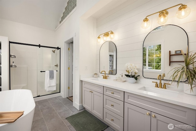 full bathroom featuring double vanity, a shower stall, a freestanding bath, and a sink