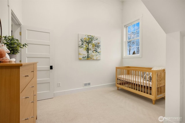 carpeted bedroom with visible vents, a crib, baseboards, and vaulted ceiling