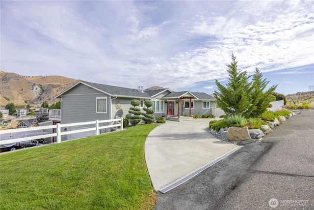 ranch-style house with a front lawn, fence, and a mountain view