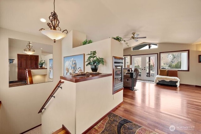 interior space featuring french doors, vaulted ceiling, baseboards, and wood finished floors