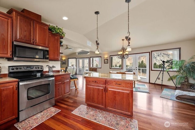 kitchen featuring dark wood-style floors, french doors, appliances with stainless steel finishes, open floor plan, and vaulted ceiling