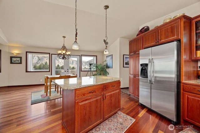 kitchen with dark wood-style flooring, a kitchen island, vaulted ceiling, stainless steel fridge with ice dispenser, and glass insert cabinets