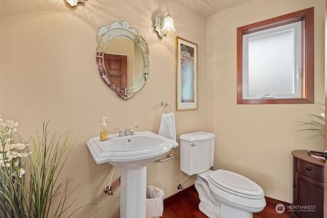 bathroom with baseboards, toilet, and wood finished floors