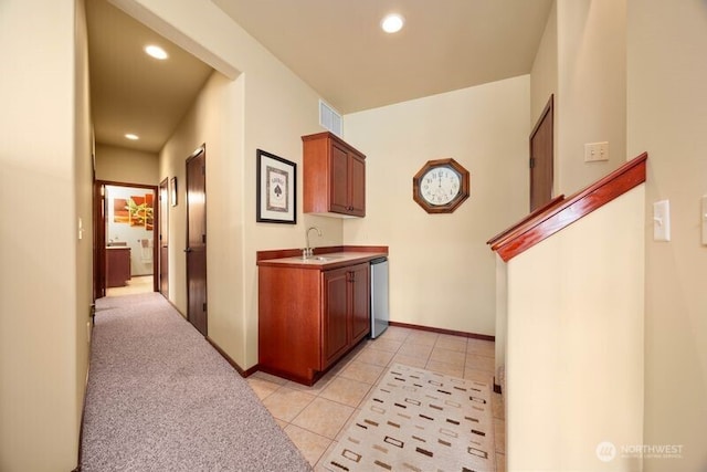 hallway featuring light tile patterned floors, recessed lighting, visible vents, a sink, and baseboards