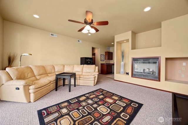 carpeted living area with recessed lighting, visible vents, ceiling fan, and a glass covered fireplace